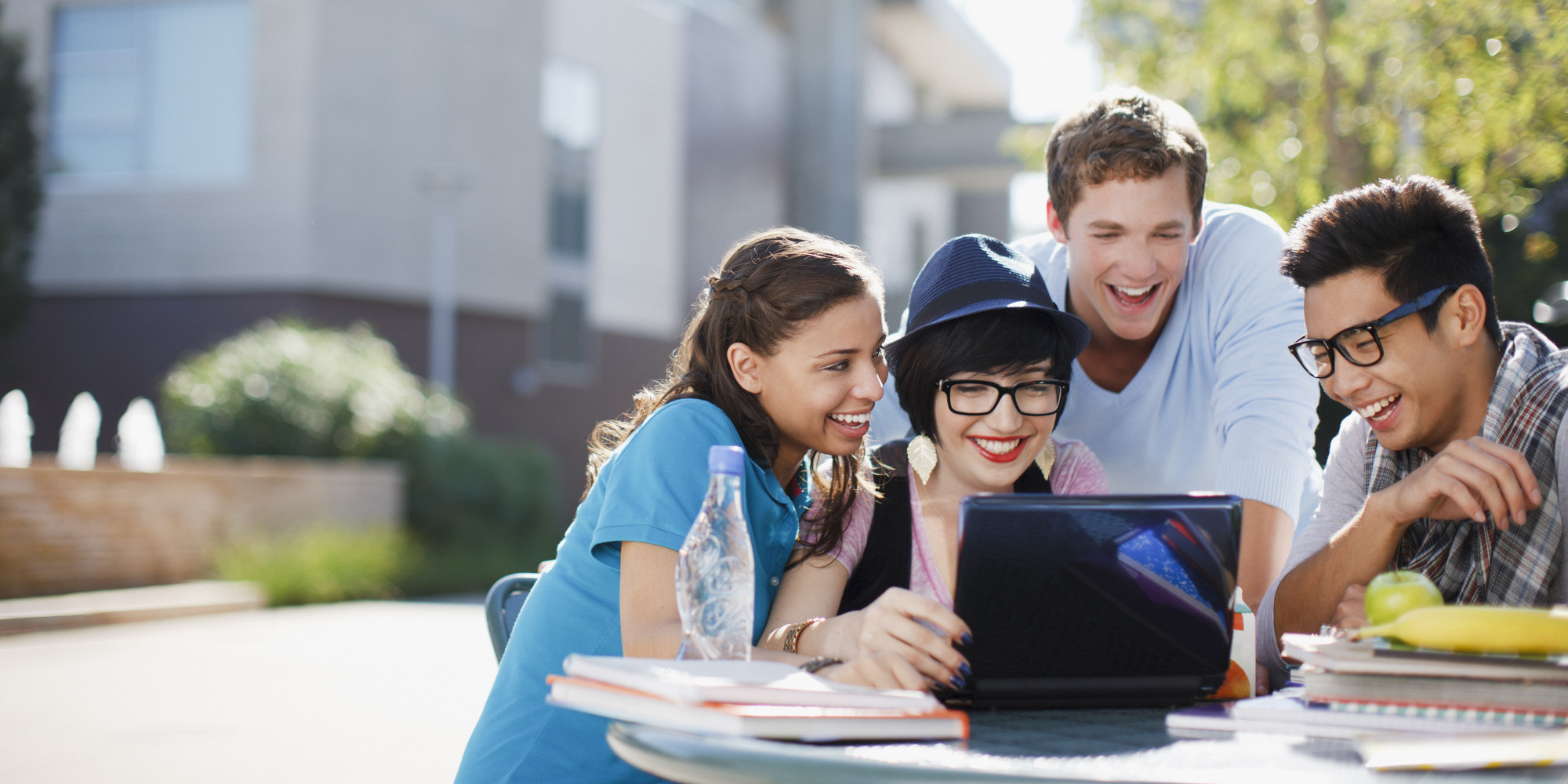 Students using laptop together outdoors